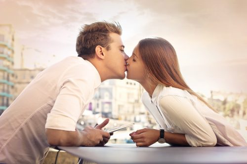 テーブルを挟んでキスする男女