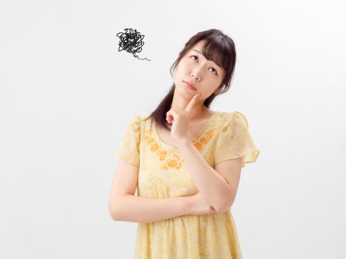 首を傾げて考える女性