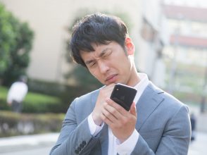 ケータイ見て悩む男