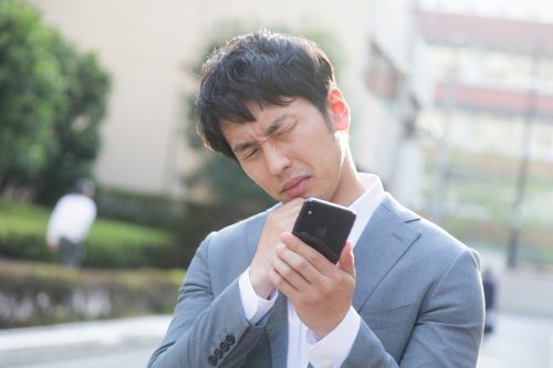 ケータイ見て悩む男