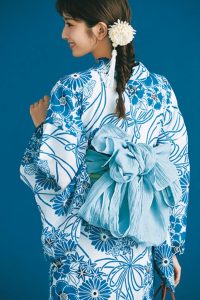 水色の浴衣の着用写真を後ろから撮影したもの。サイドで束ねた髪の毛には、白い花の飾りがついている。