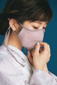 淡いピンクのマスクを着用した顔アップ写真。左側から撮影。