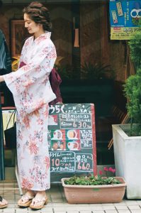 白地に水彩風の花柄が描かれた浴衣。帯はえんじ色。